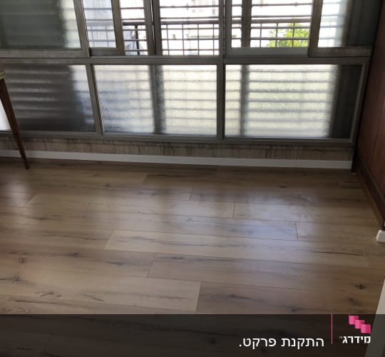 רצפת פרקט עץ בהירה בחדר עם חלון גדול